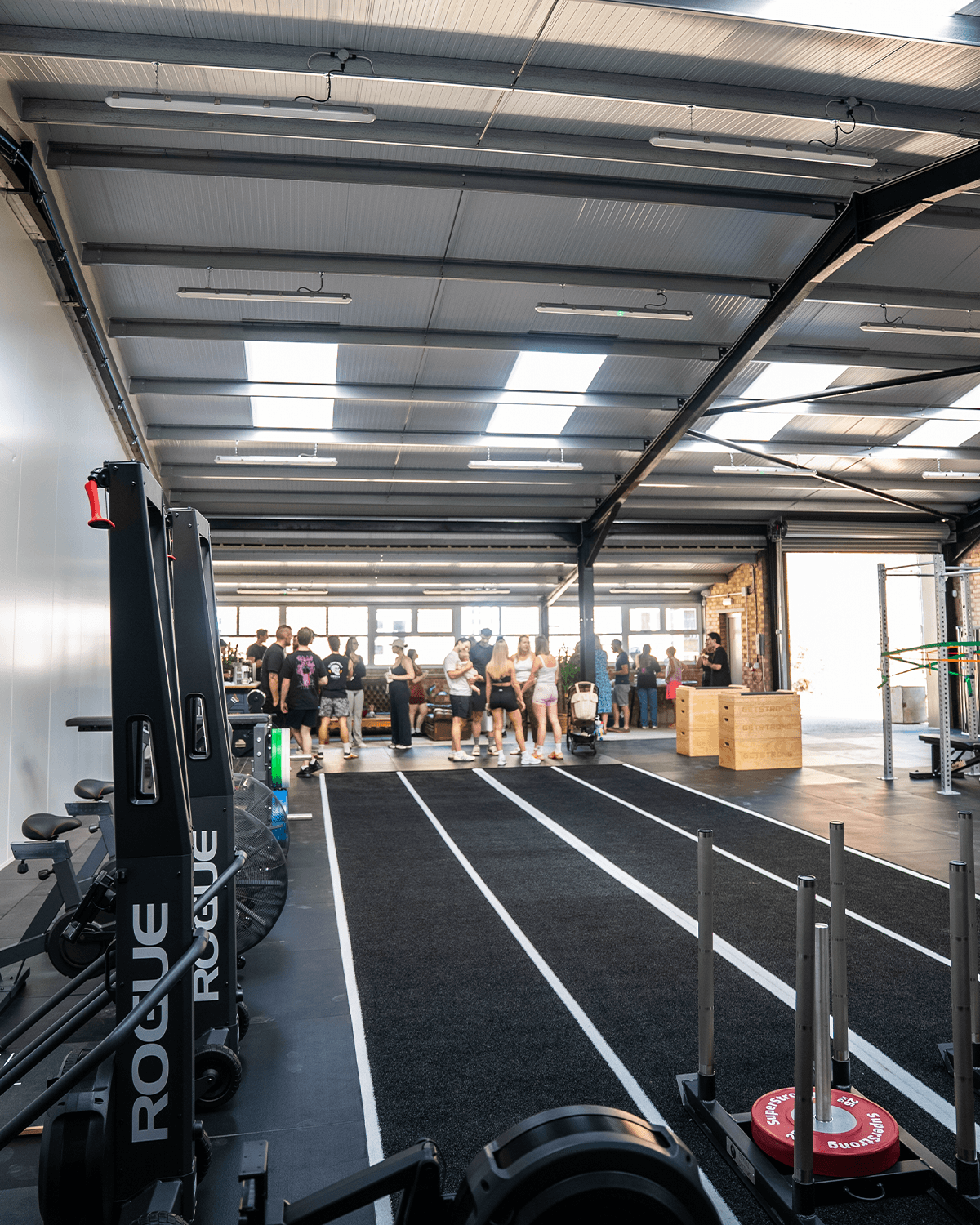 Members and guests gathered on the gym floor near the sled track during an open day at Magni Fitness.